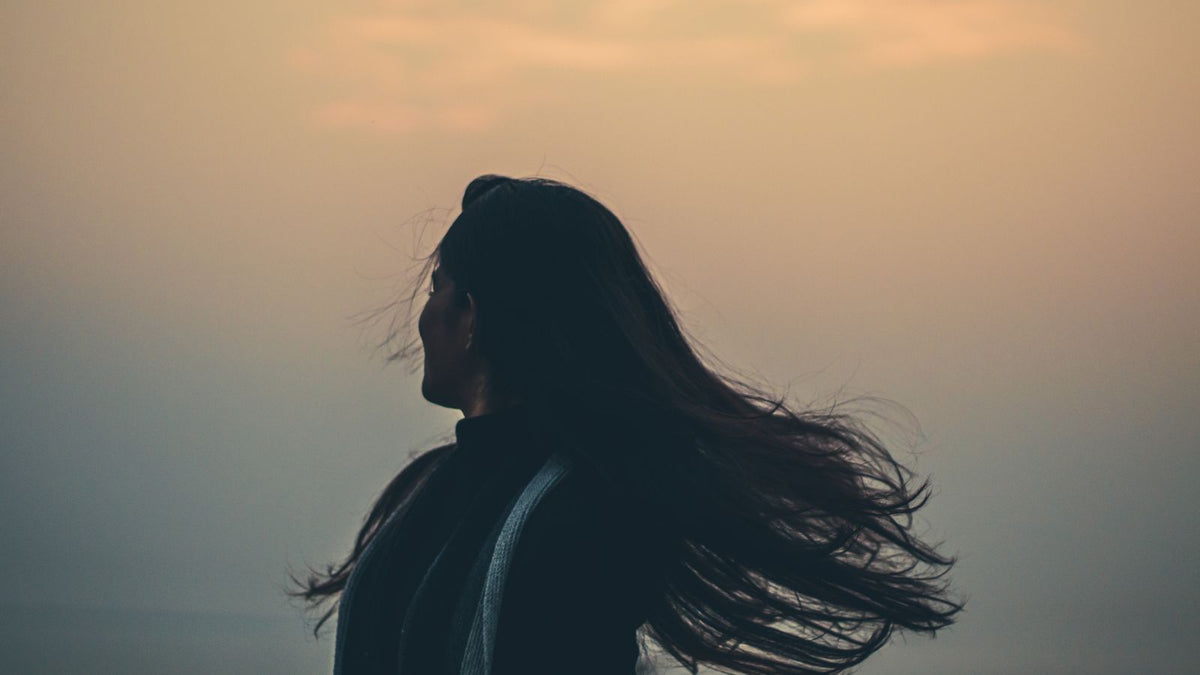 Woman shaking out long hair, a healthy anagen telogen ratio in action