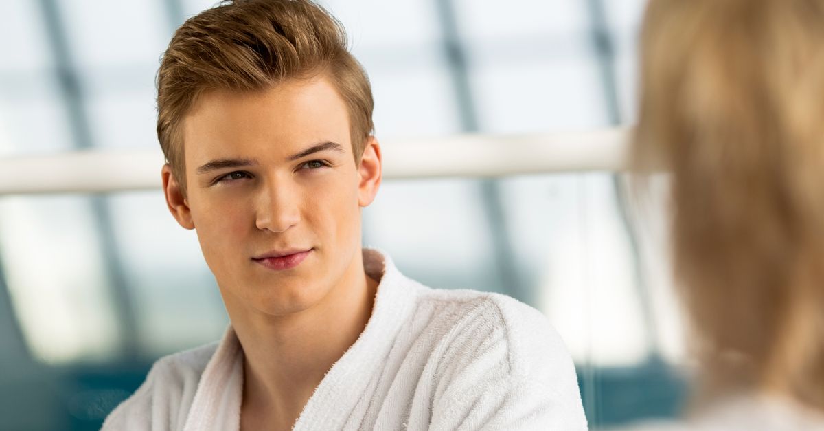 A man at home by a window, the everyday setting where androgen receptor expression first shows as a change in hair pattern