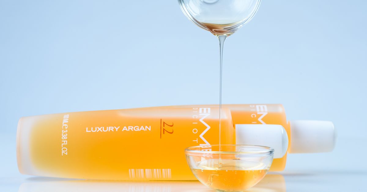A bottle of argan oil beside a wooden comb, a classic finishing oil for hair