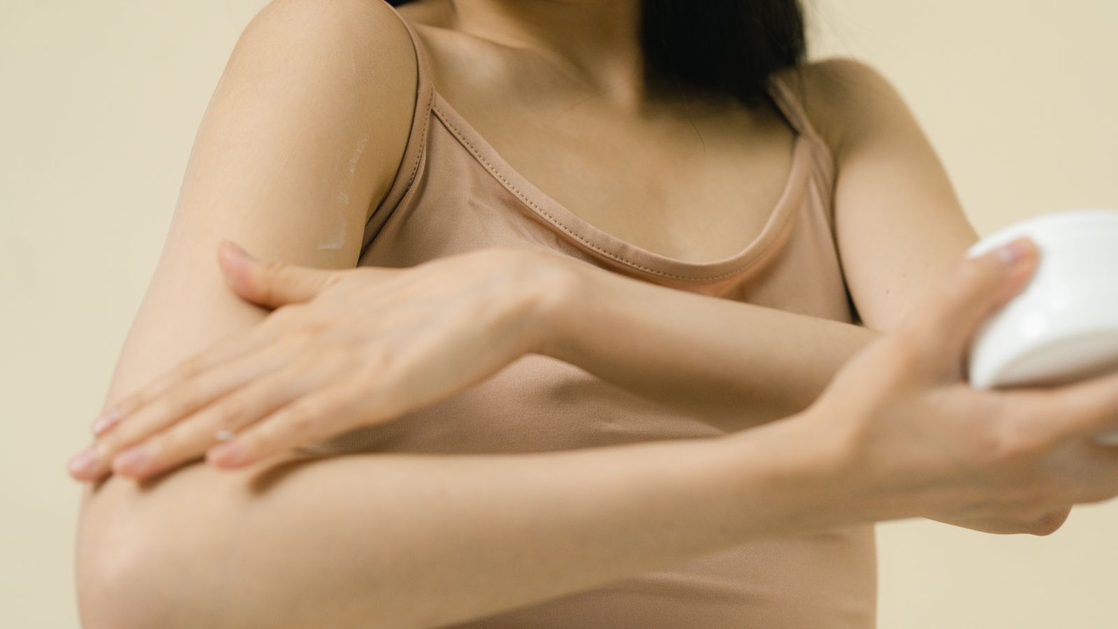 Woman smoothing moisturiser along her arm as part of a simple body care routine