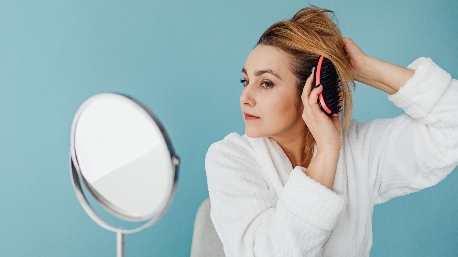 Woman checking her hair in the mirror, covid hair loss after infection