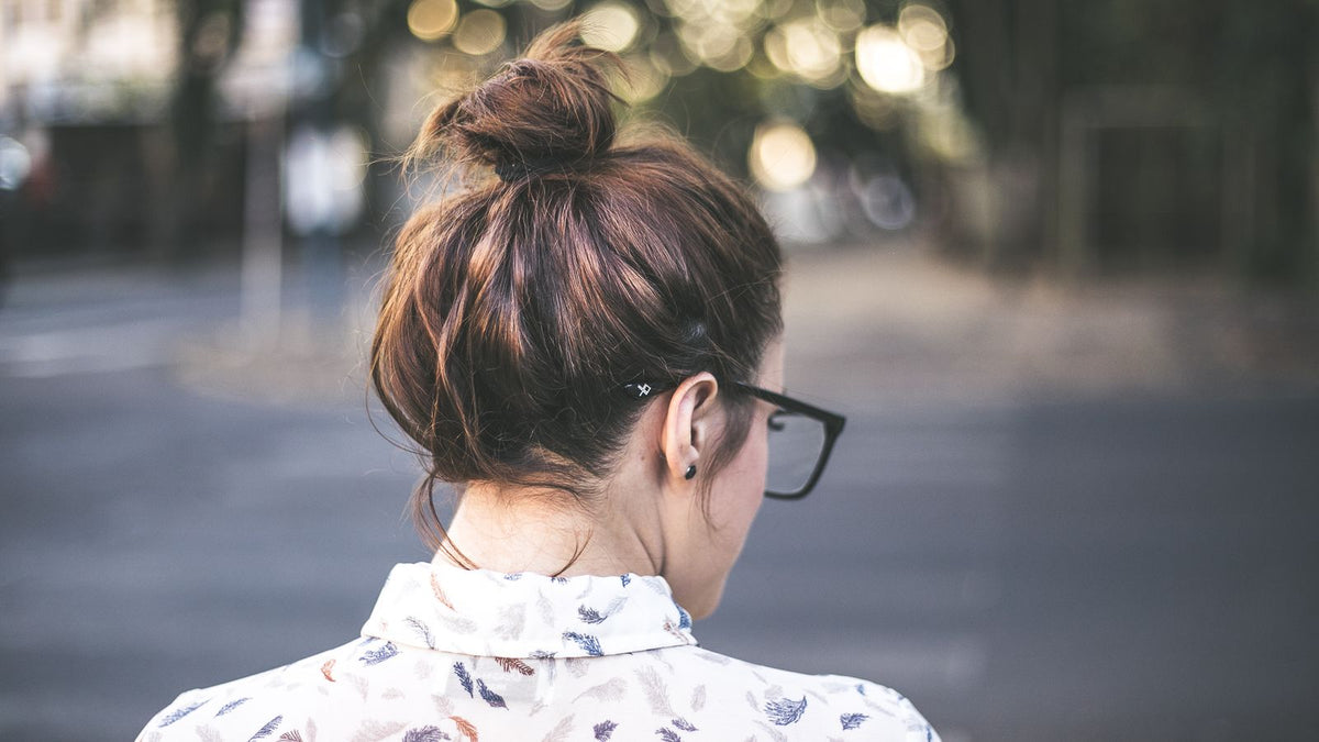 Back view of a woman with her hair in a bun, the crown area where crown hair growth is easiest to judge