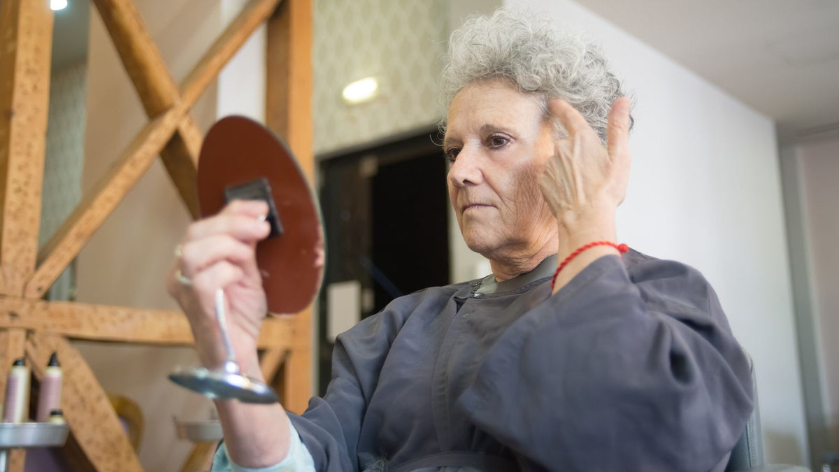 Woman checking her new hairstyle in a mirror while worried about estrogenic alopecia