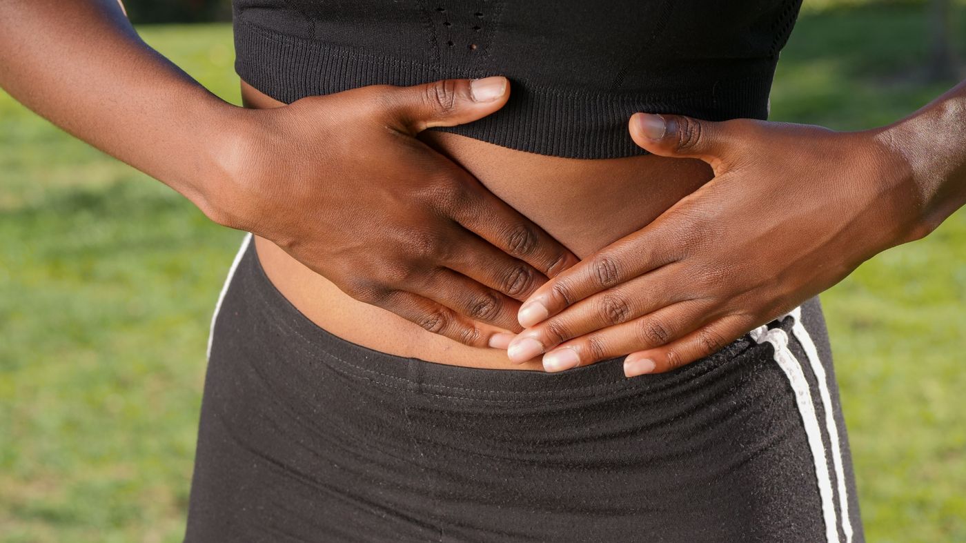 Person holding their stomach with abdominal pain, one of the common fat malabsorption symptoms