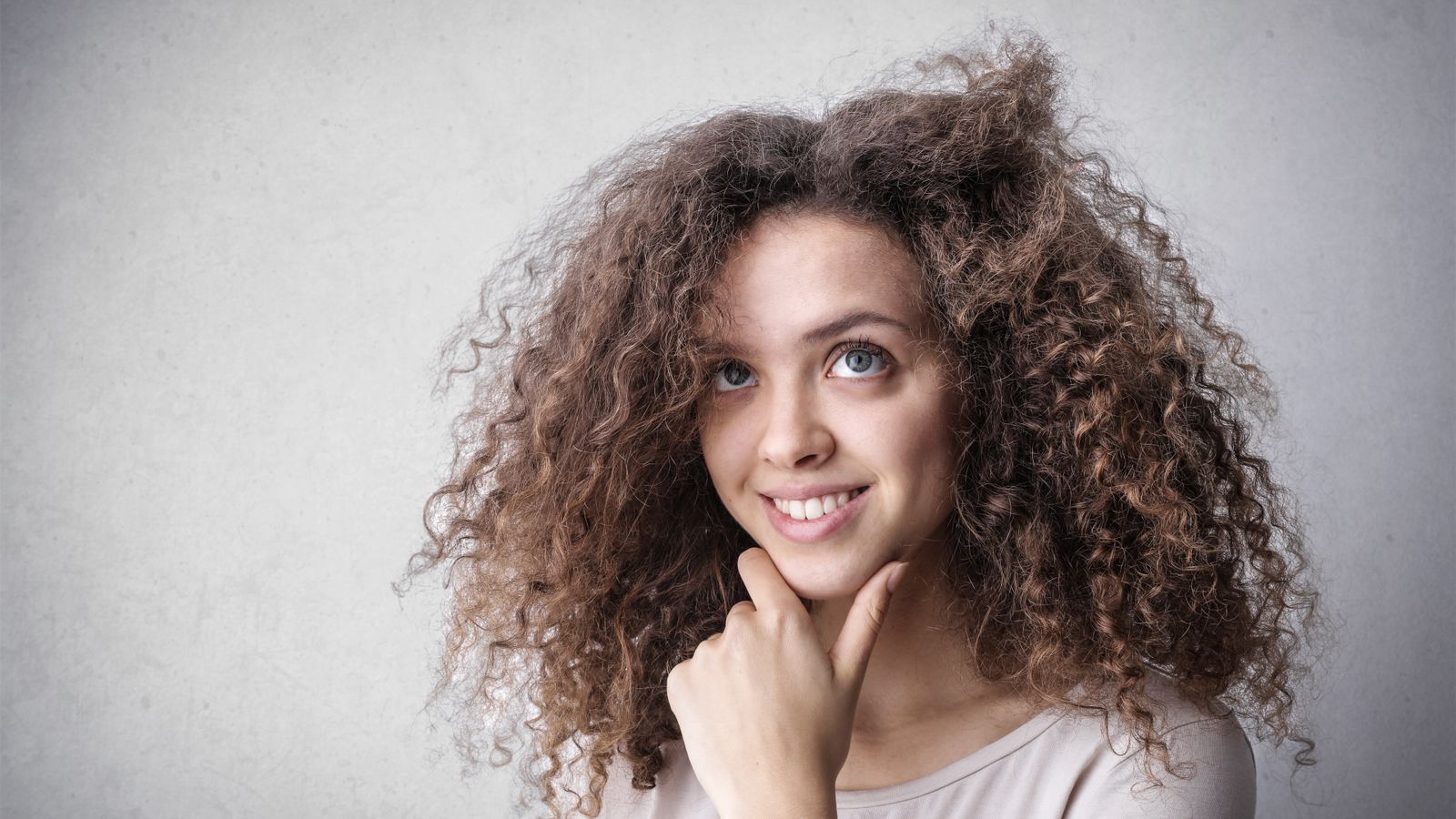 Woman with frizzy hair smiling, illustrating a guide to caring for frizzy hair