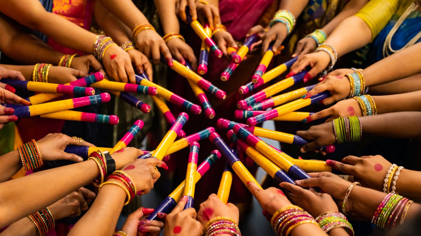 Dandiya sticks raised during a Navratri celebration, the nine nights that make garba hair care necessary