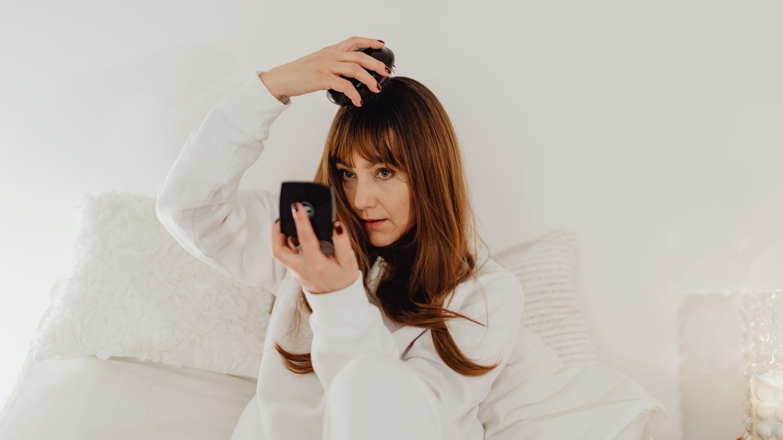 Woman combing her hair at home, dealing with greasy roots between washes