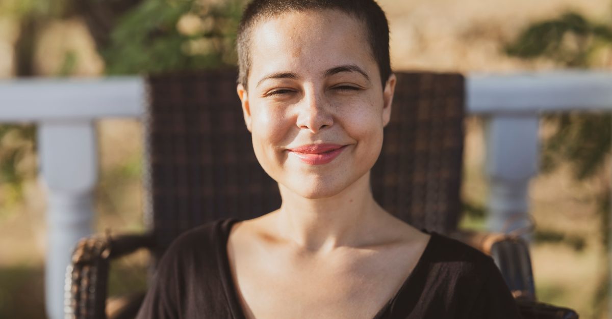 Smiling person with a buzz cut outdoors, hair care during gender affirming care at every length
