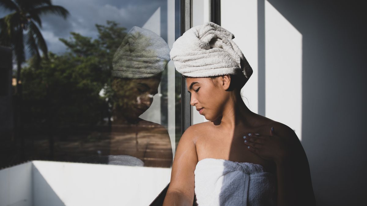 Woman with a towel after washing her hair, the moment most people first notice hair falling out in shower water