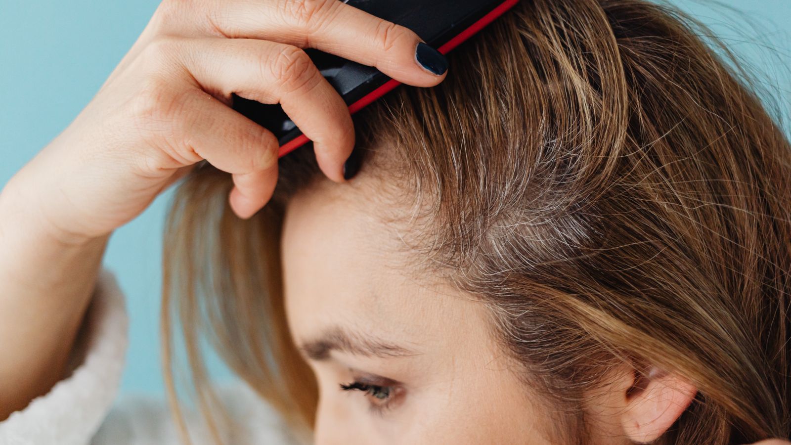 Woman brushing her hair and looking at the strands, an everyday sign of hormonal hair thinning