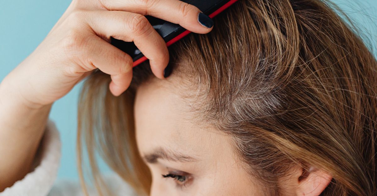 Woman brushing her hair and checking hormone therapy hair density at the parting