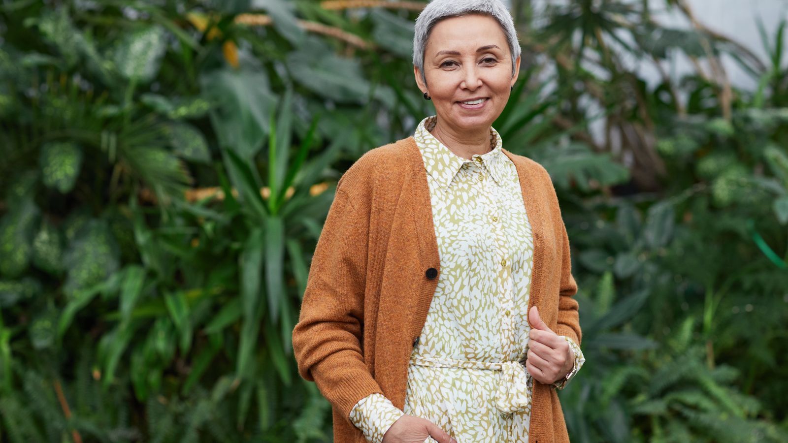 Smiling older woman in a greenhouse, realistic expectations for hormone therapy hair regrowth