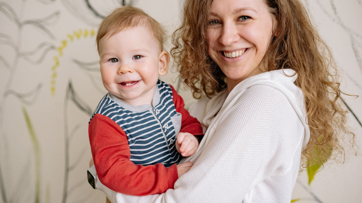 Happy mother holding her smiling baby, wondering how long does postpartum hair loss last