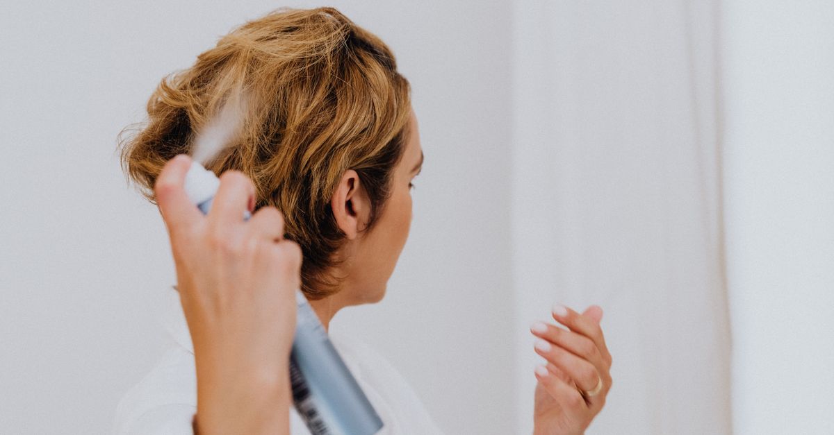 Woman applying a product to her hair at home, illustrating how often to apply a hair product