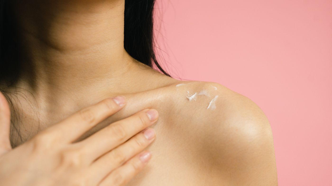 How to apply fake tan evenly: woman smoothing self-tanner over her shoulder