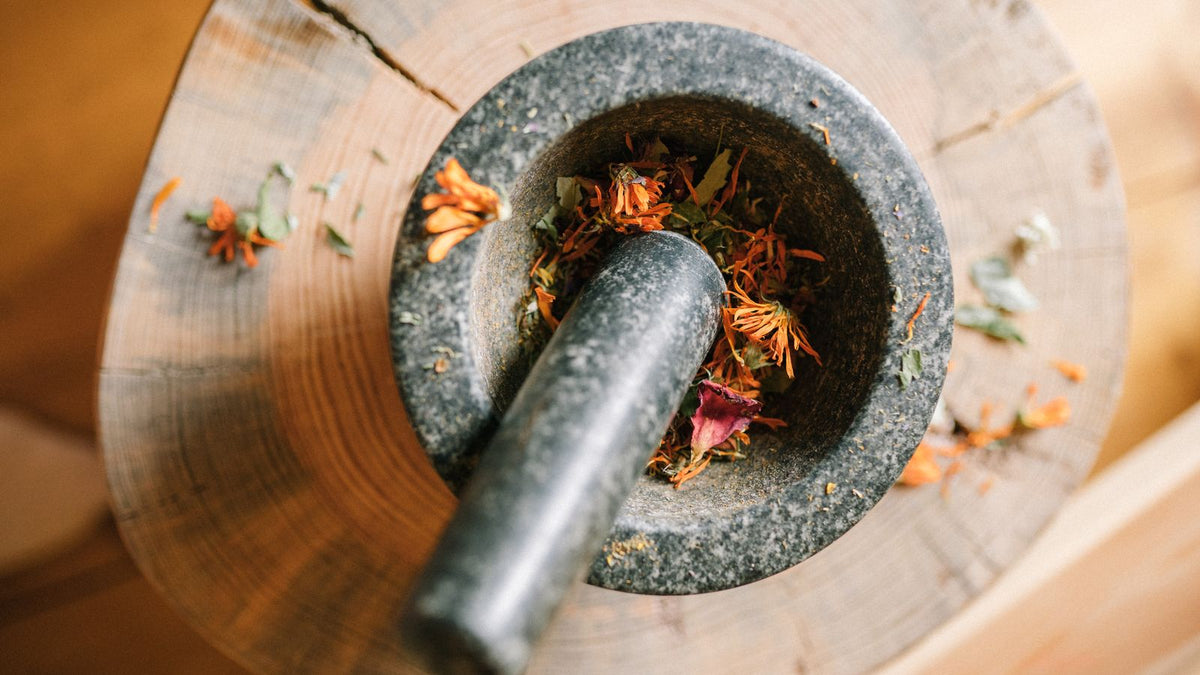 Mortar and pestle grinding dried herbs, the traditional way to prepare brahmi powder for hair