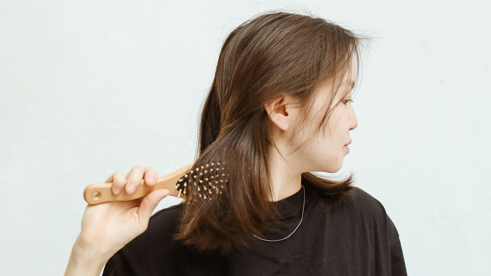 Woman applying conditioner to the lengths of her hair, showing how to use conditioner properly