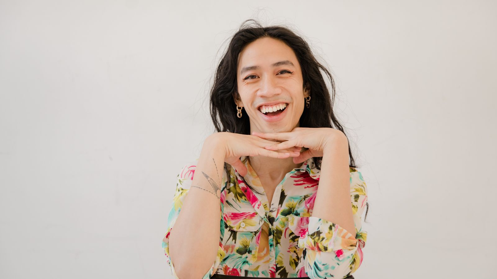 Smiling person with long hair in a floral shirt, HRT hair texture changes during hormone therapy