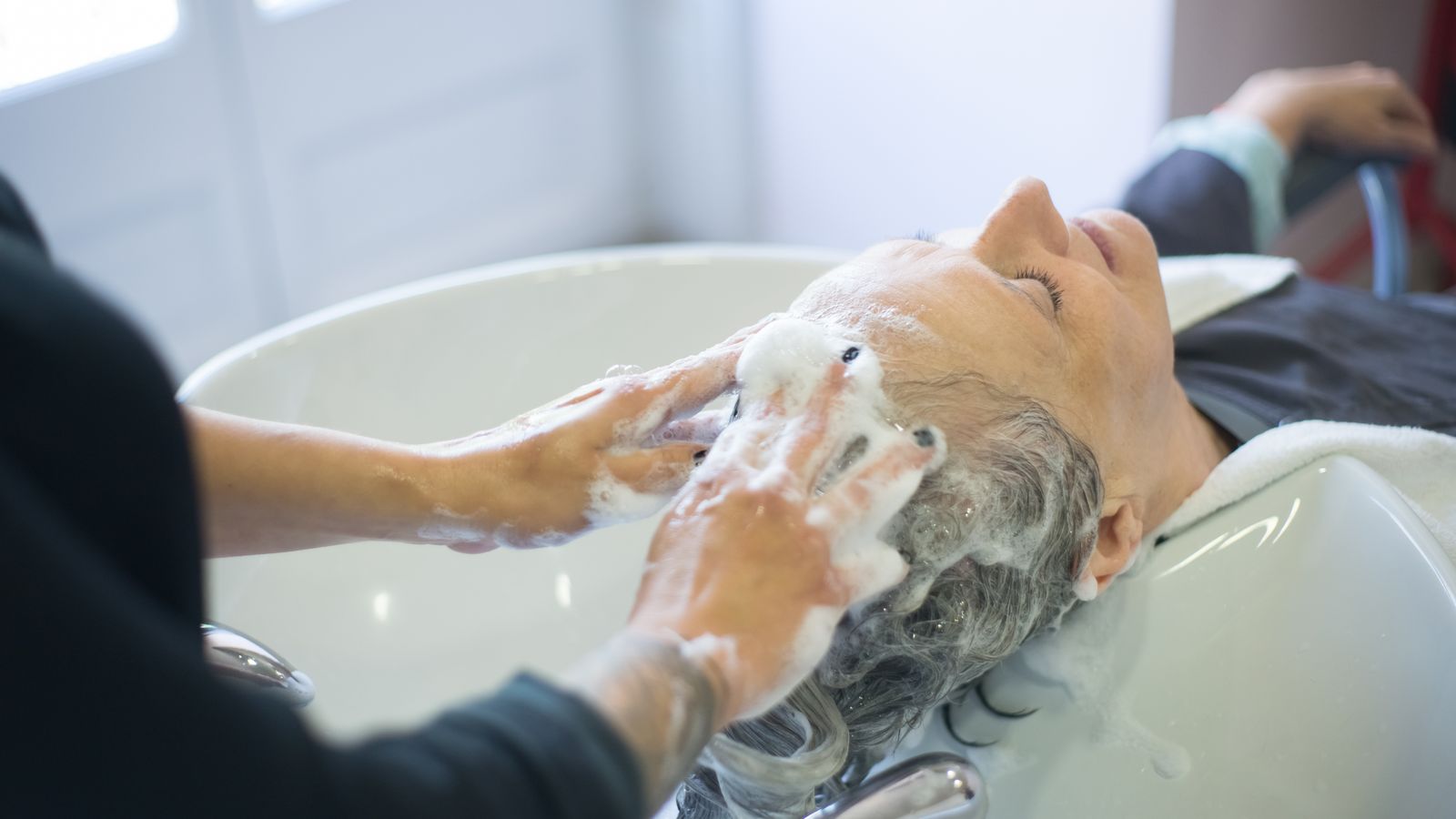 Close up of a scalp being washed at a salon, the scalp condition behind the question is a derma roller good for hair growth