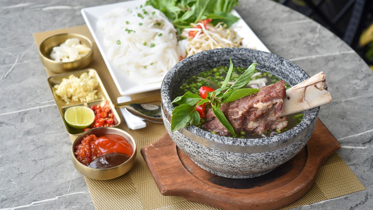 A bowl of beef bone broth with noodles and herbs, illustrating whether bone broth is good for hair growth