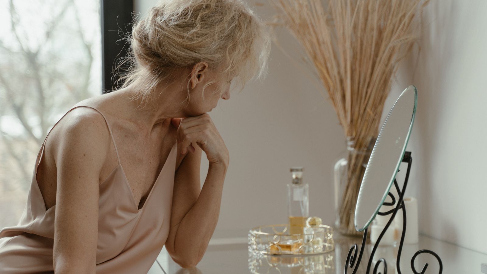 Woman over 40 checking her hair in the mirror and wondering is hair loss normal for a woman