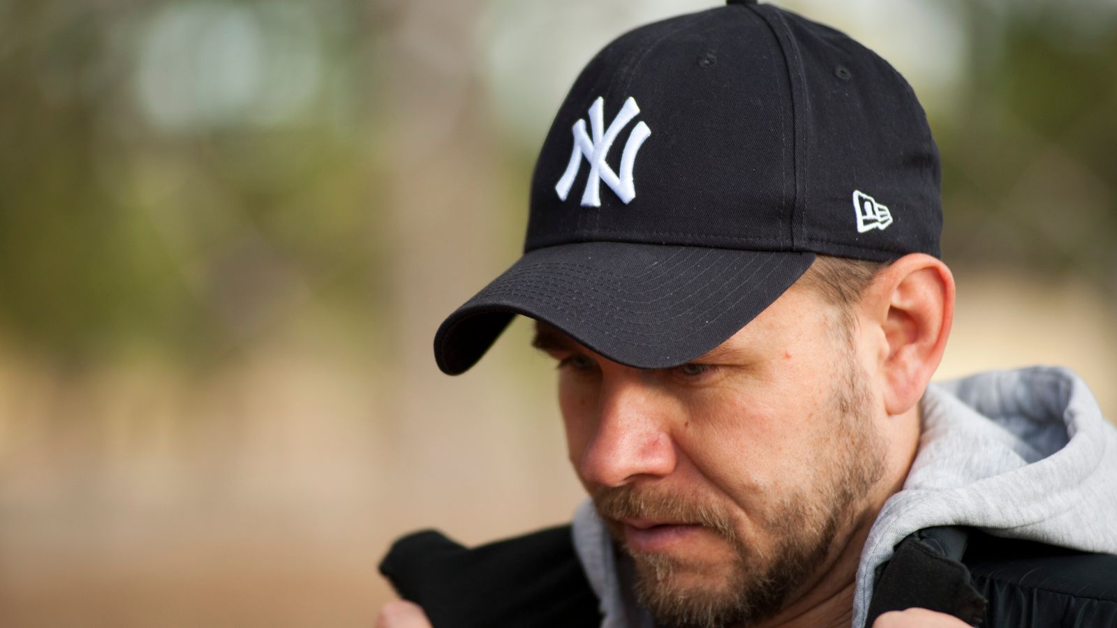 Man in a baseball cap outdoors, asking is wearing a hat everyday bad for your hair