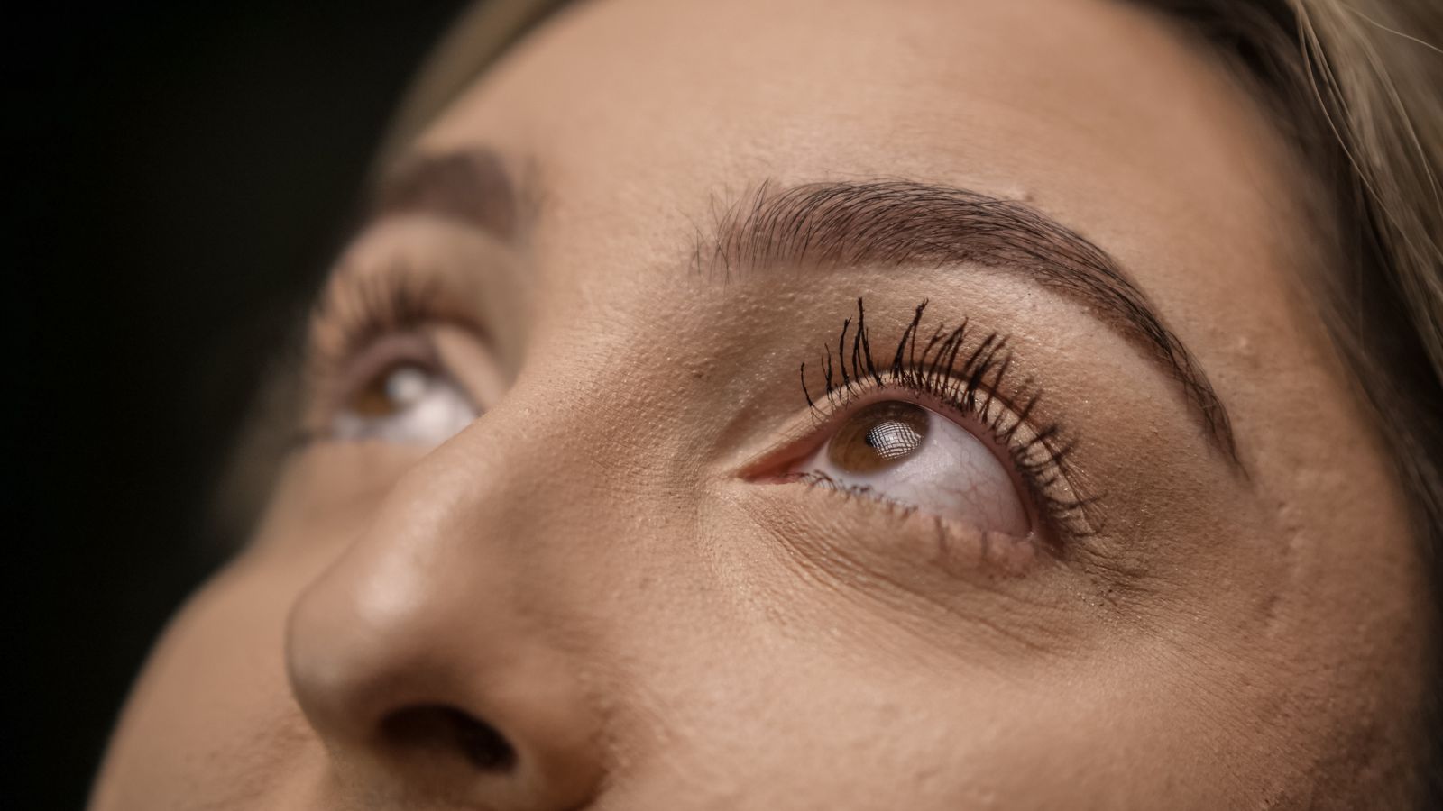 Close-up of a woman's eyes with long natural lashes, illustrating everyday lash and brow care