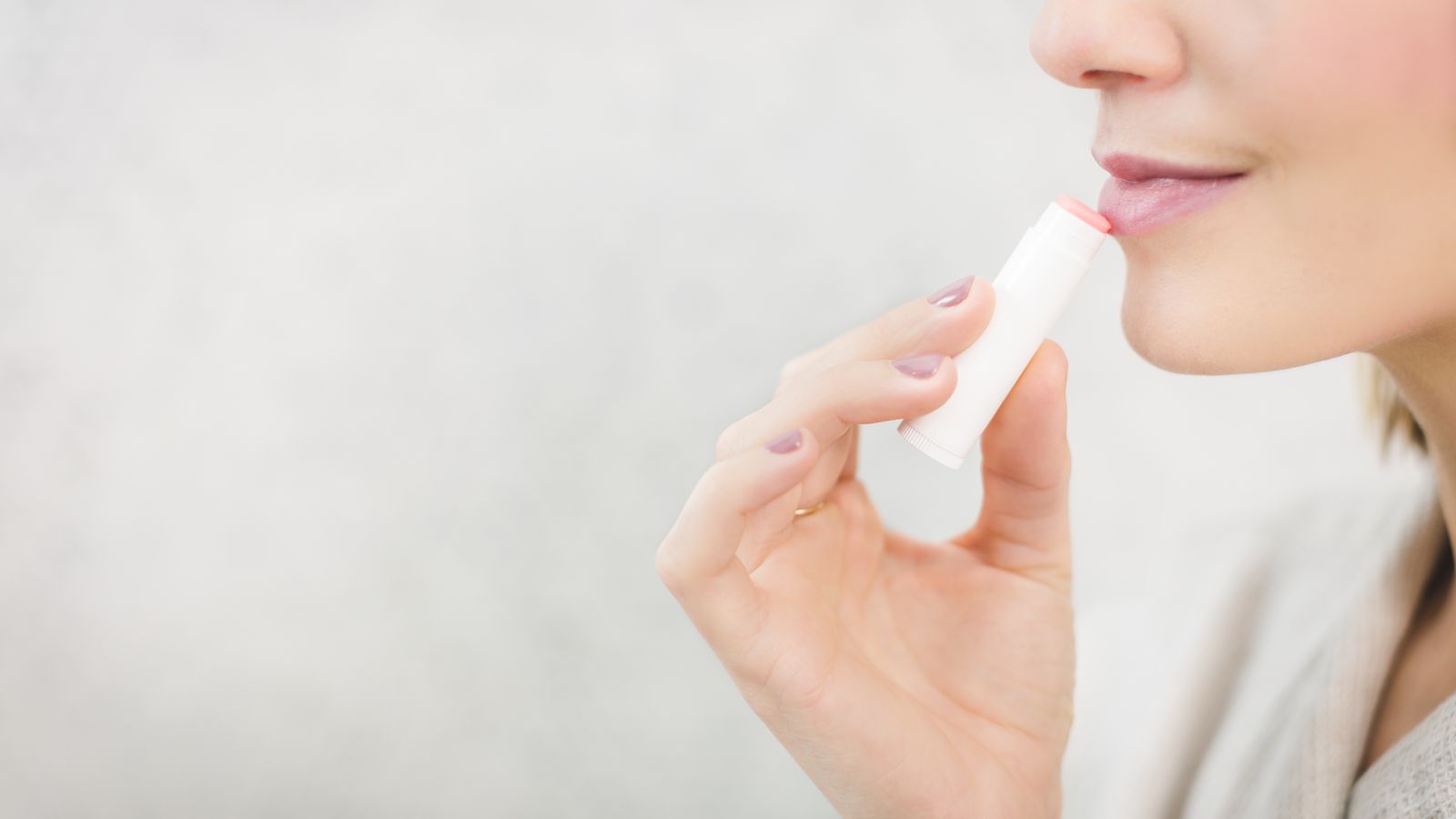 Woman applying an SPF lip balm, the simplest way to use lip sunscreen every day