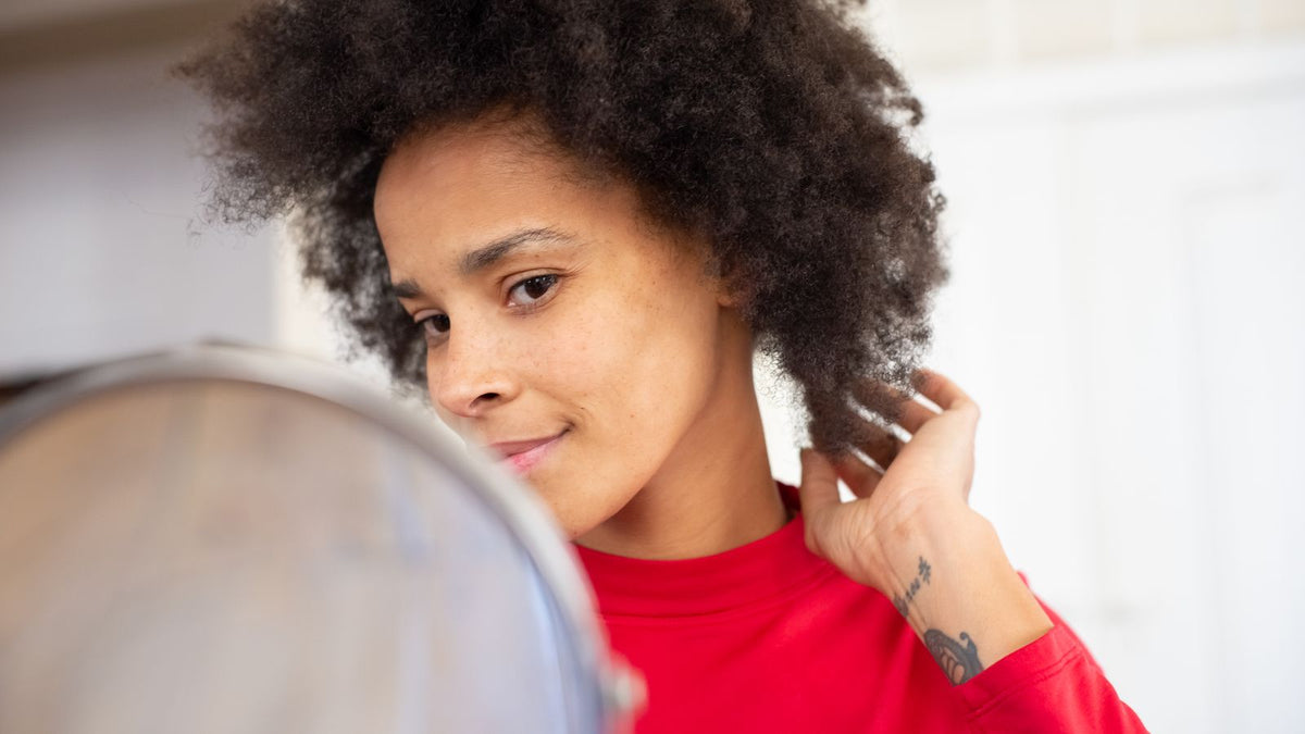 Woman checking her hair in a mirror, the moment most people notice medication related hair shedding