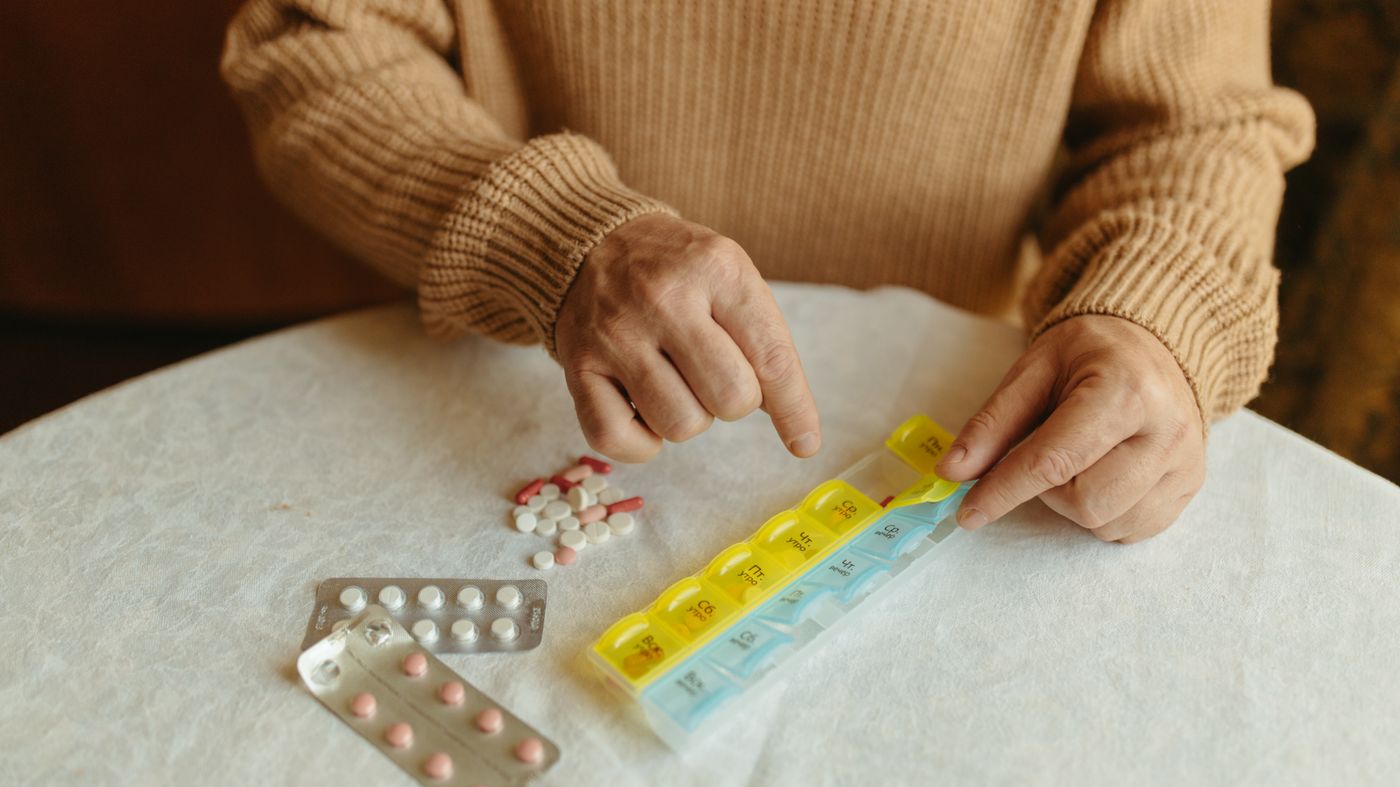 Older adult sorting a weekly pill organiser, reviewing medications that can cause dementia symptoms