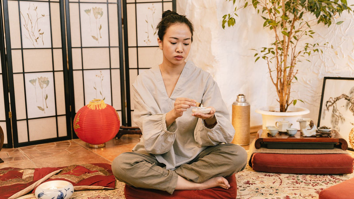 Woman meditating calmly by candlelight, meditation for hair growth and everyday stress management
