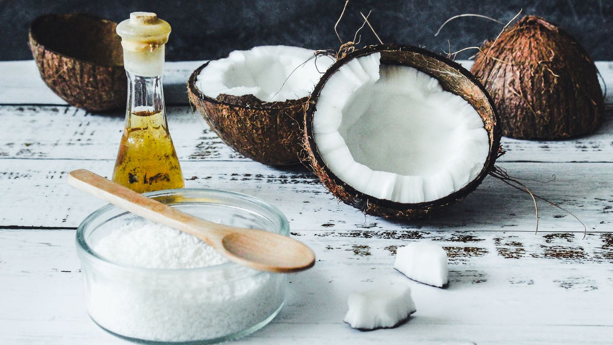 Coconut oil, flakes and whole coconuts on a wooden board, a classic natural hair strengthener