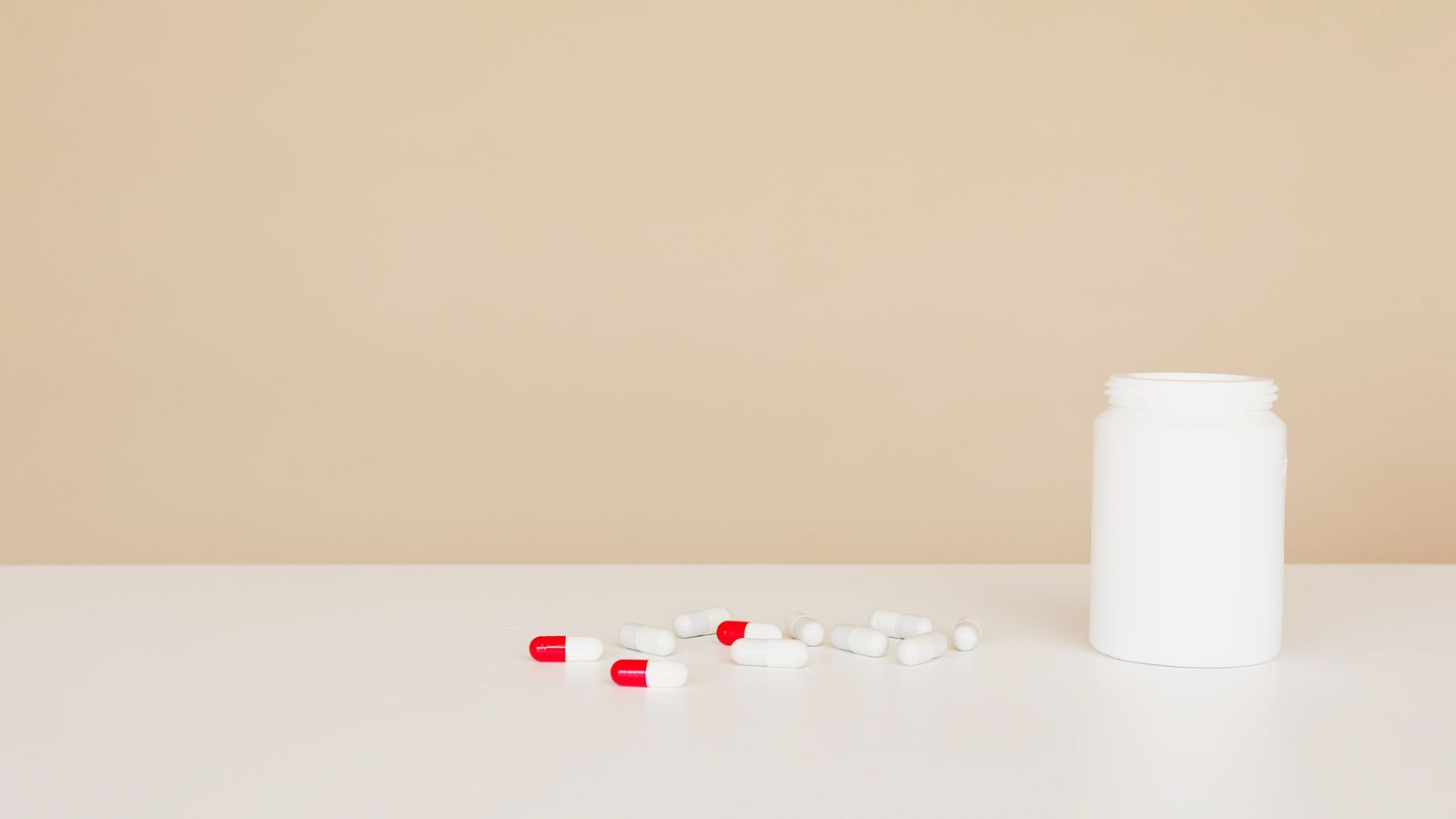 Medicine bottle and tablets representing oral vs topical minoxidil options