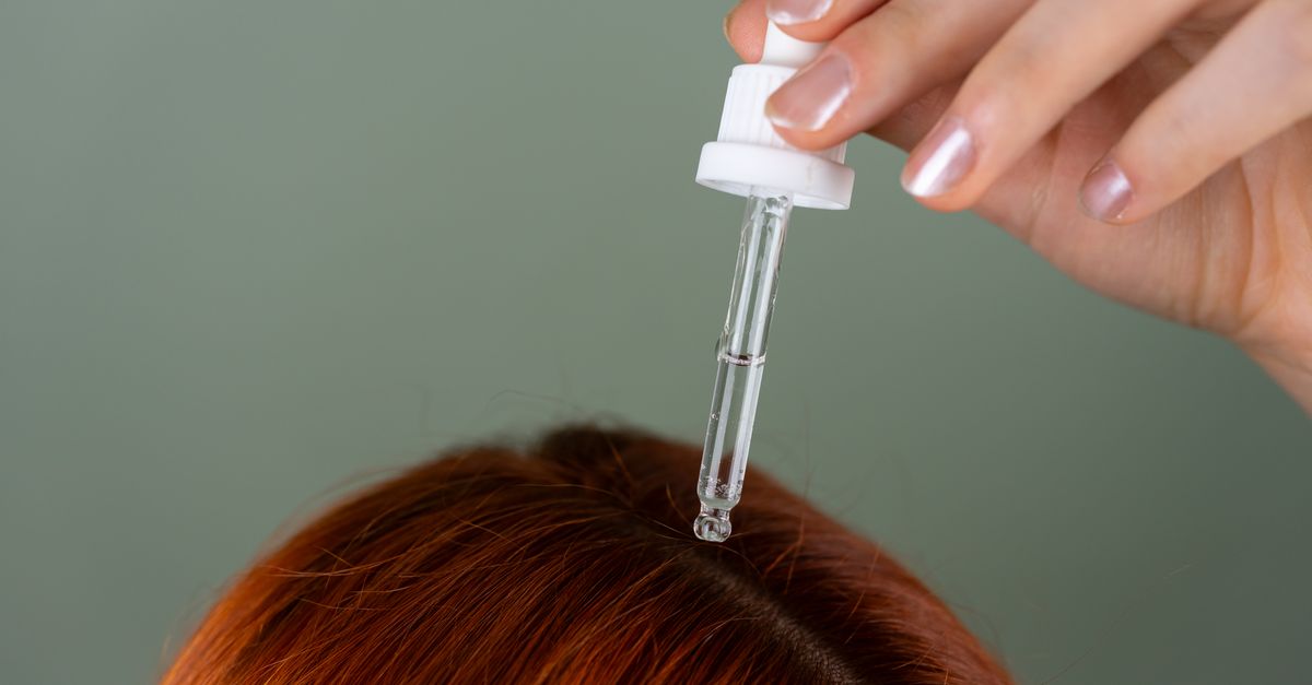 Applying batana hair oil with a dropper to the scalp