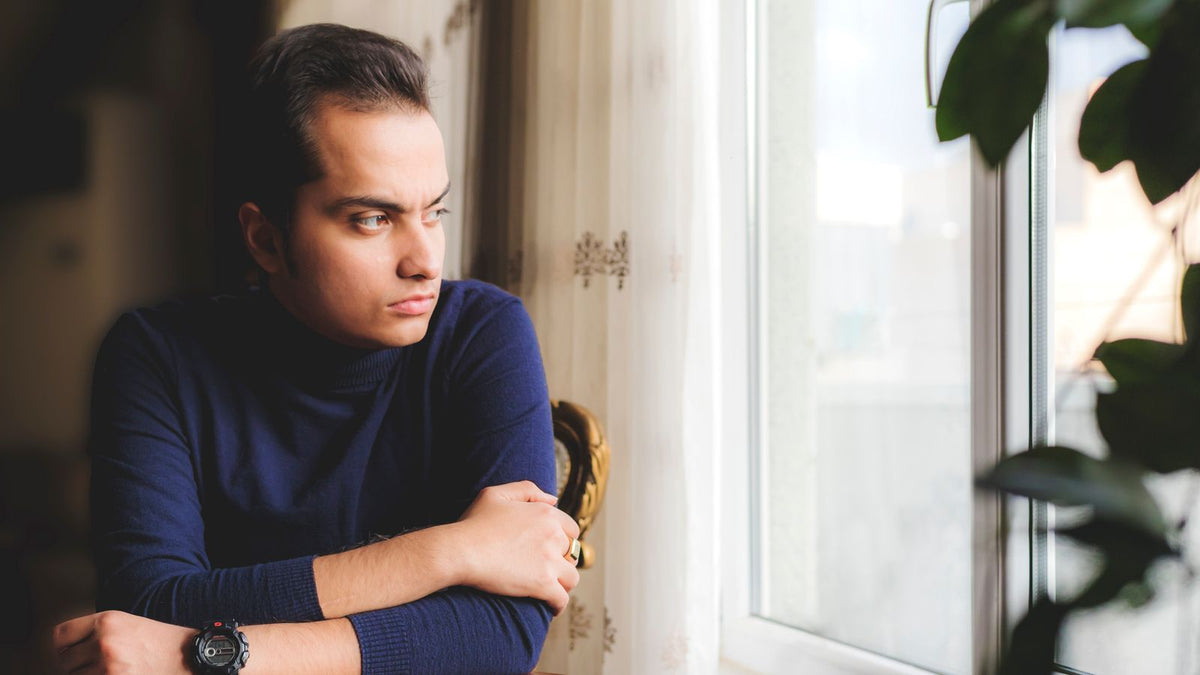 Man considering post orchiectomy hair changes while resting by a window