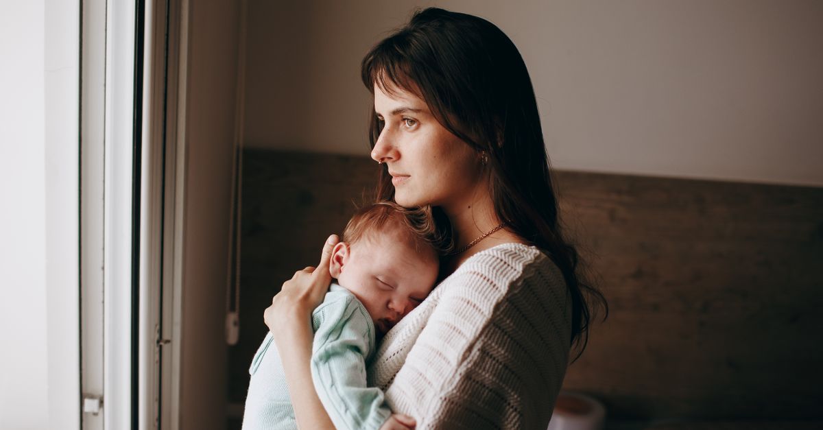 New mother in the postpartum hair loss stage holding her baby