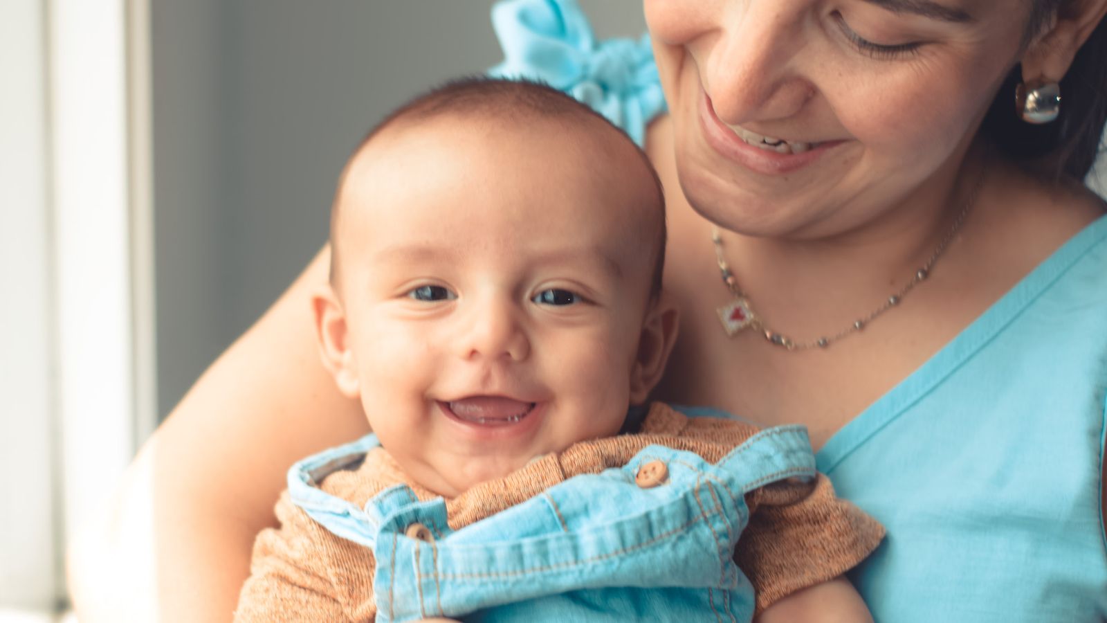 Smiling new mother holding her baby, understanding postpartum hair loss