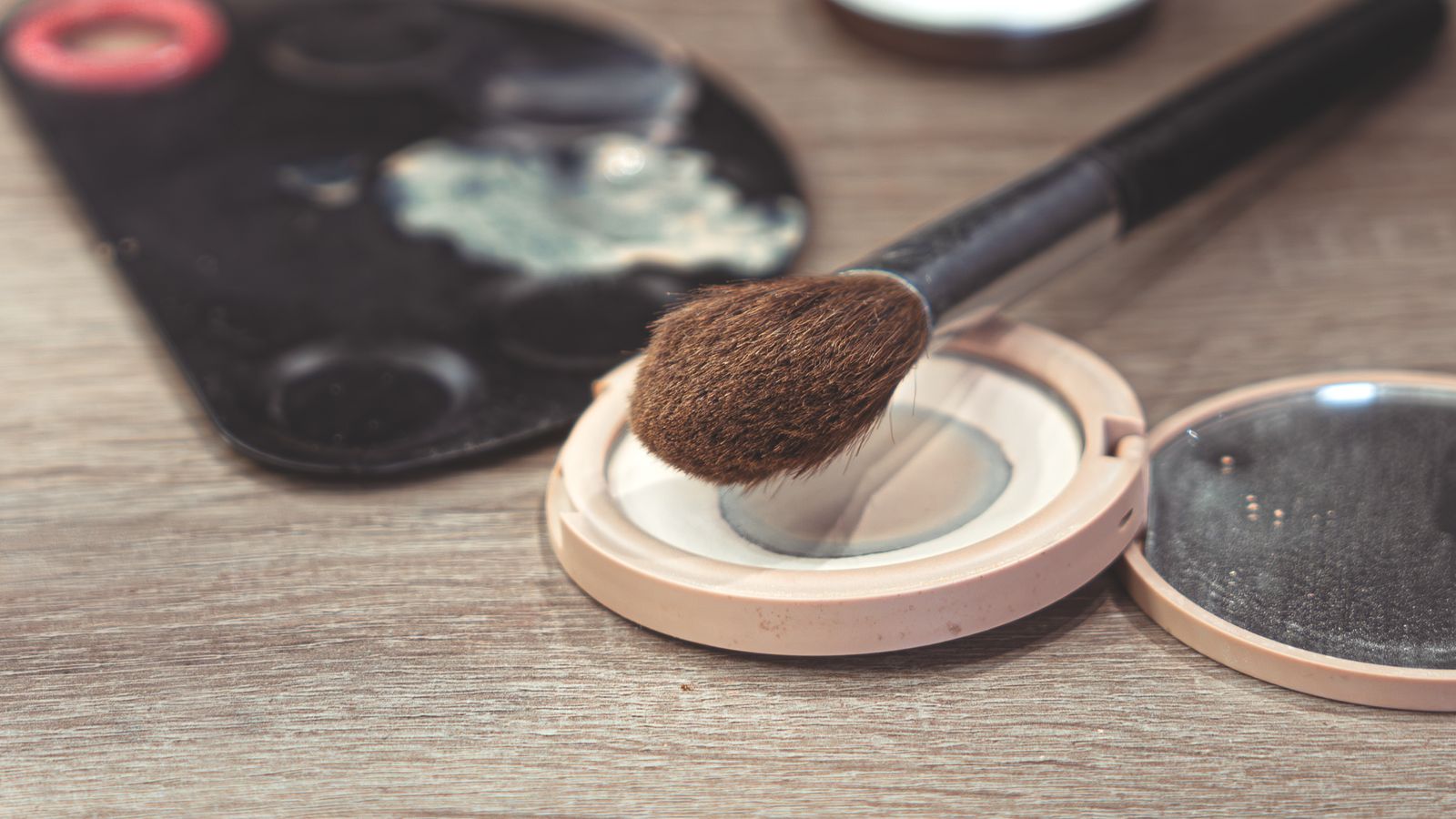 Brush resting on an open compact, the format used for powder sunscreen