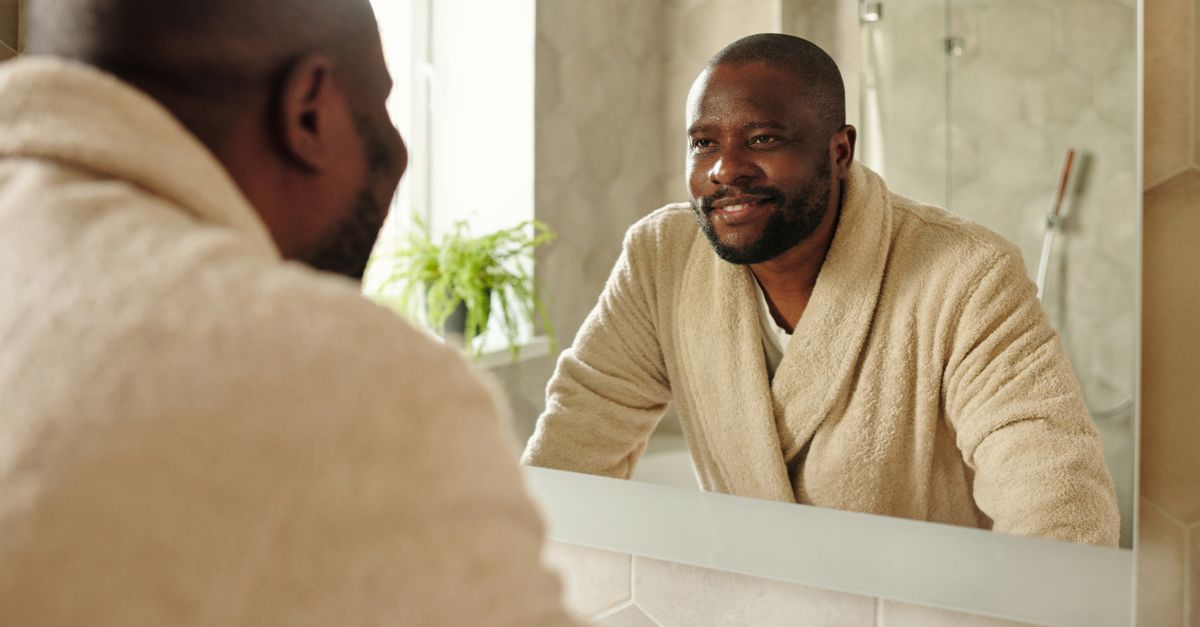 Man looking at his hairline in a bathroom mirror, checking a receding hairline