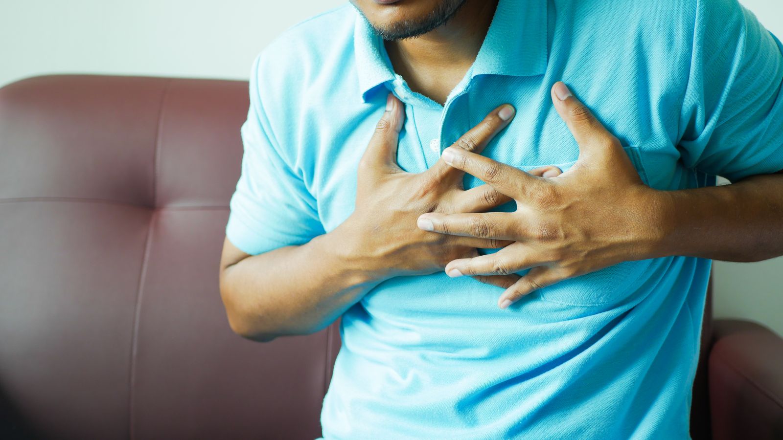 A man clutching his chest in discomfort, the central symptom in stable vs unstable angina
