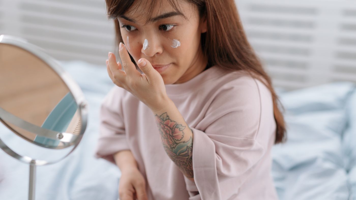 Woman applying sunscreen under makeup as part of her morning skincare routine