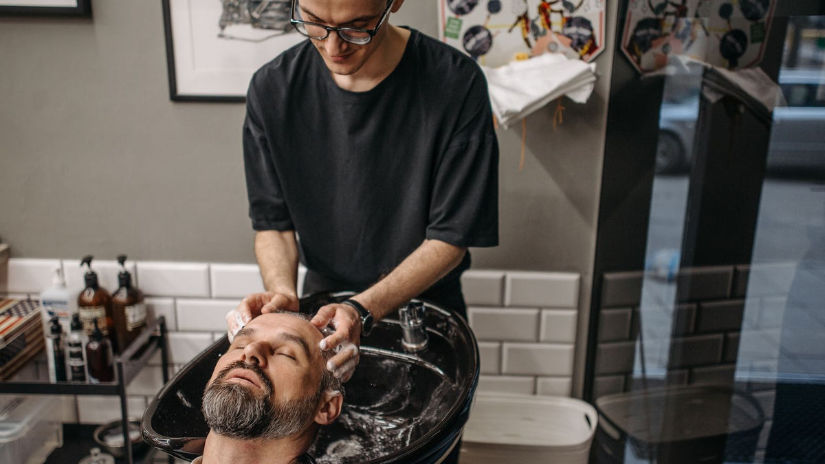 Client having hair washed at a salon basin with a thickening shampoo men can use daily