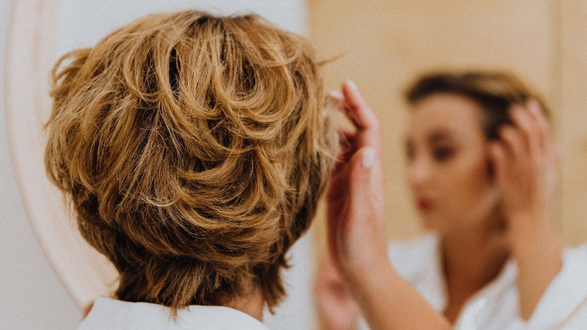 Person checking their hairline in a mirror while researching a transgender hair transplant