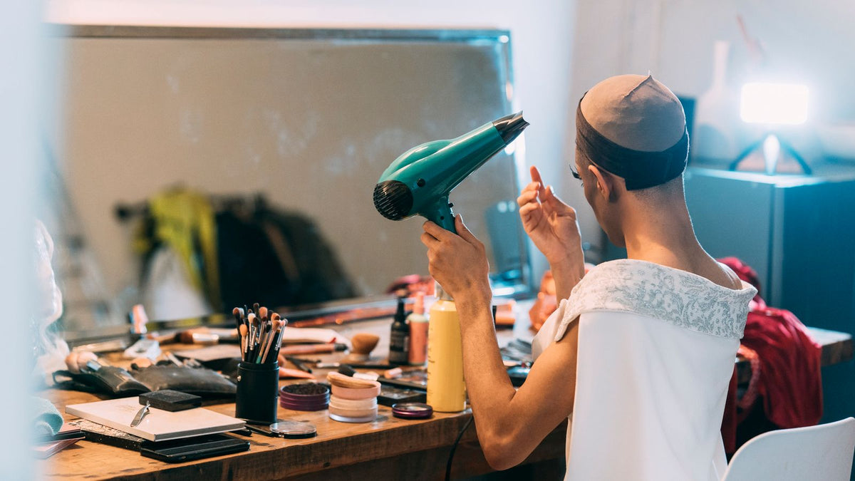 Transgender man drying his hair in front of a mirror, noticing shedding that may be transgender telogen effluvium