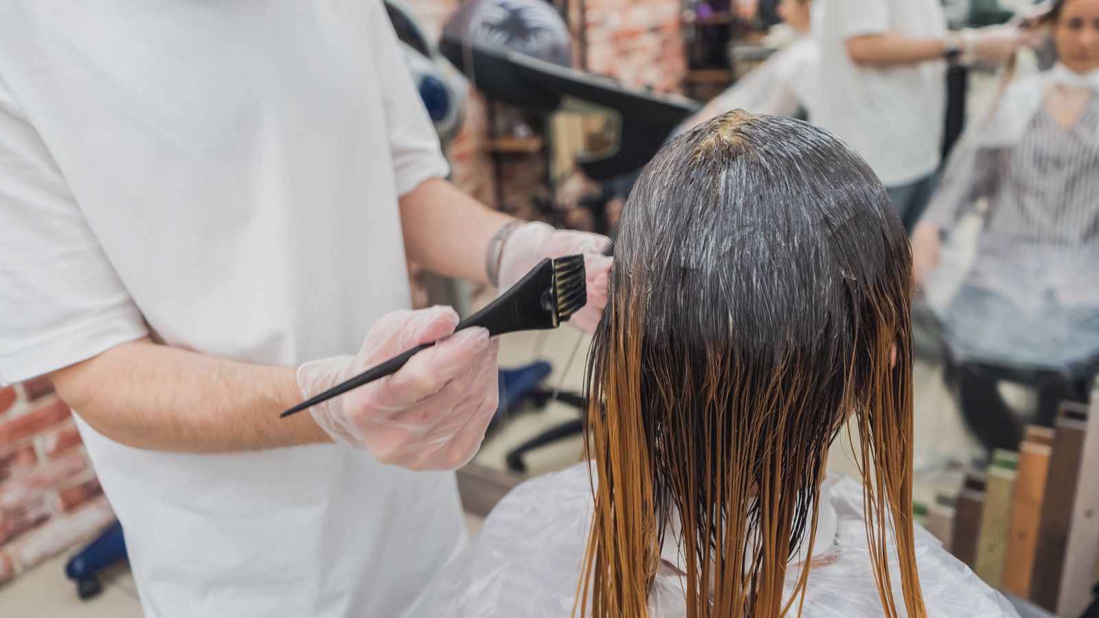 Stylist applying colour in a salon, the chemical processing a trichologist in Barnsley is often asked about