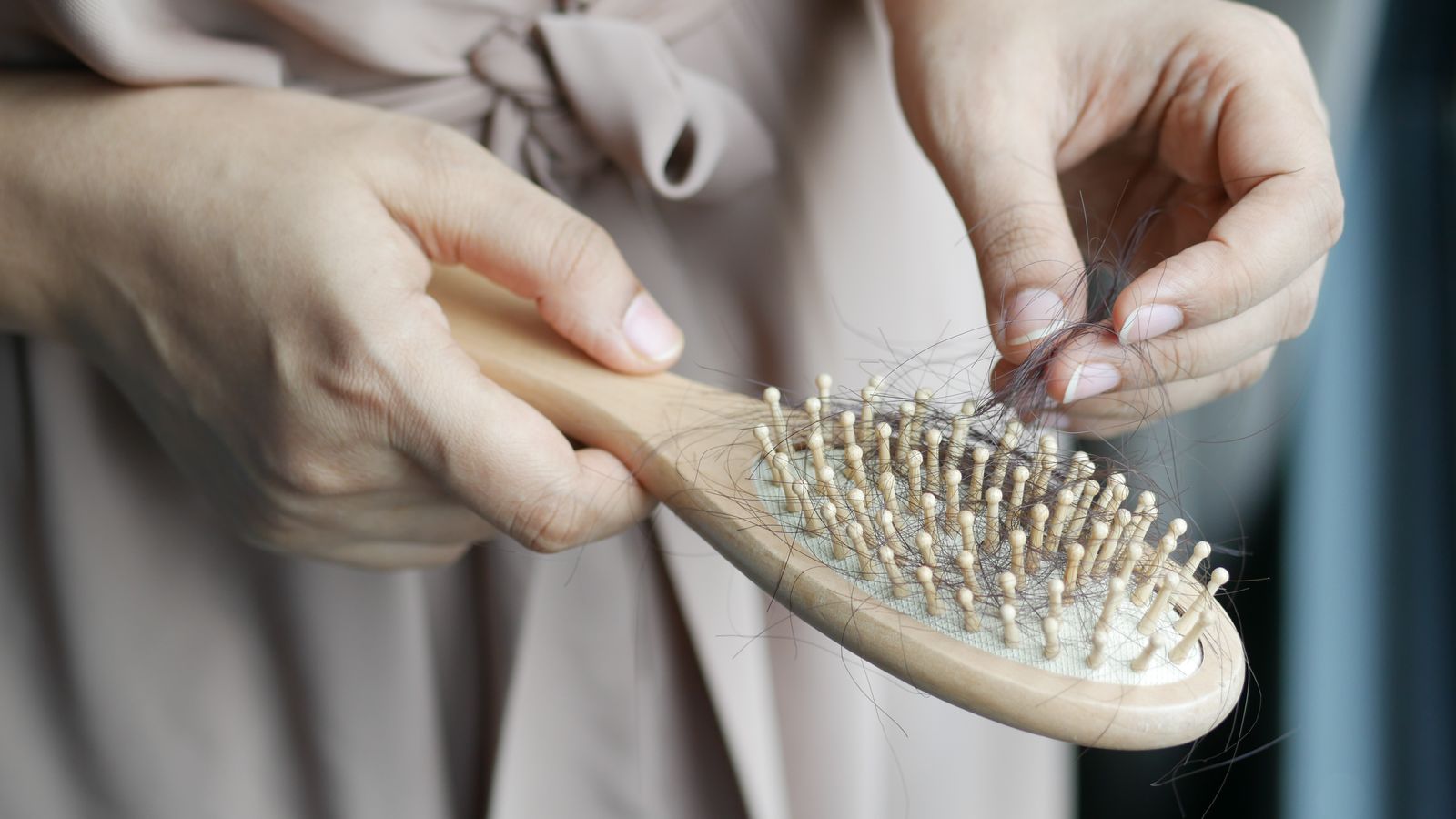Hands clearing shed hair from a hairbrush, the shedding pattern a trichologist in Darlington assesses