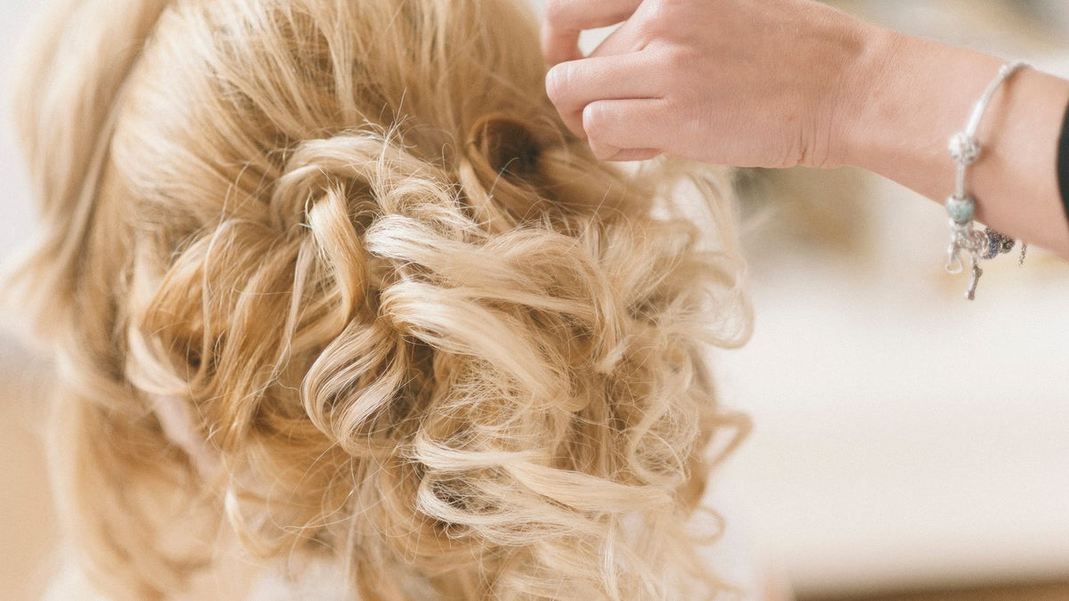 Hairstylist shaping a soft blonde bridal updo, a trichologist Dewsbury guide to wedding hair when hair is fine or thinning