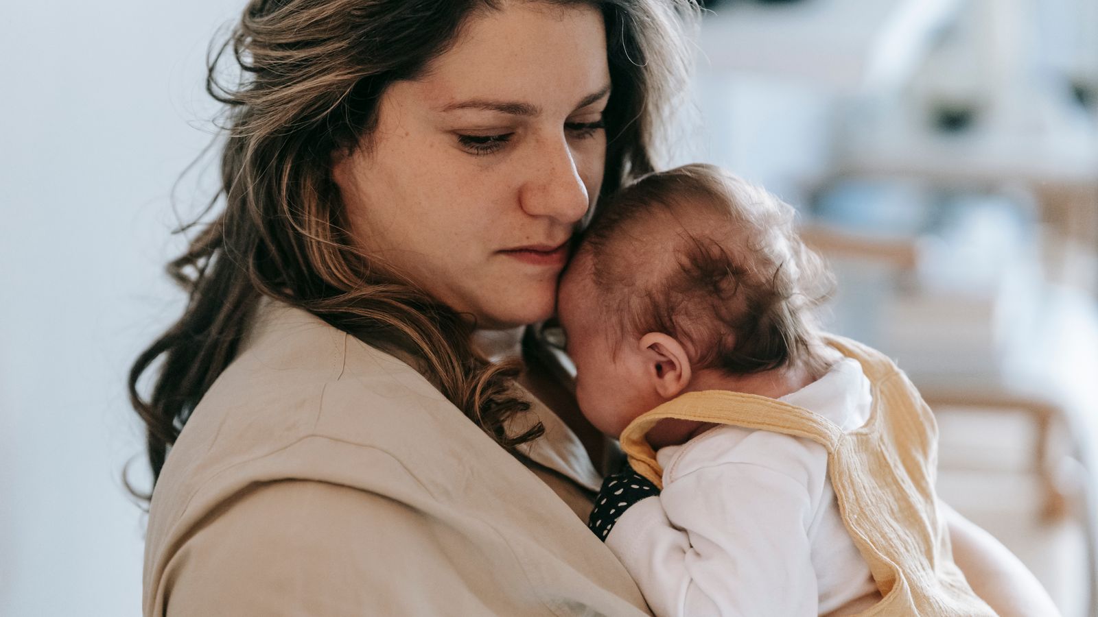 Mother holding her baby, the postpartum stage a trichologist in Merton often sees shedding after
