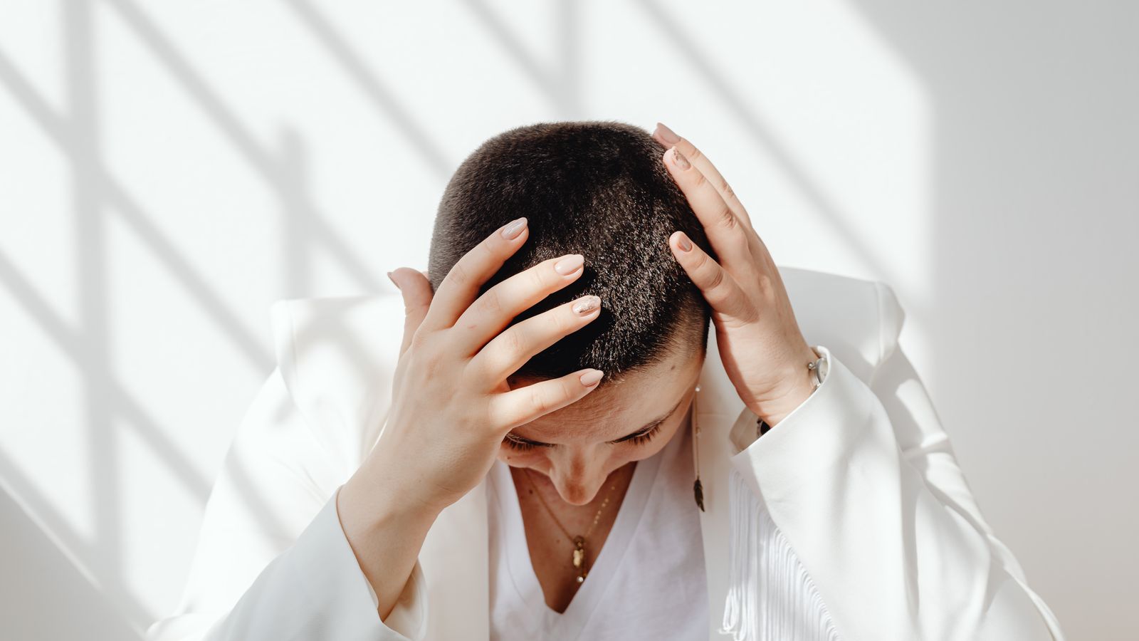 Woman sitting with her hands on her head under stress, the trigger a trichologist in Morpeth hears about most
