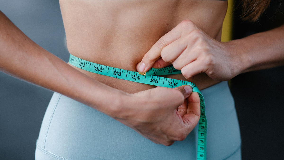 Woman measuring her waist after weight loss, the trigger a trichologist Redbridge sees for shedding